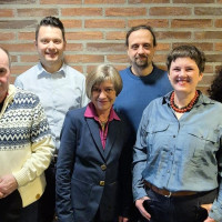 Sechs Personen vor einer Ziegelmauer