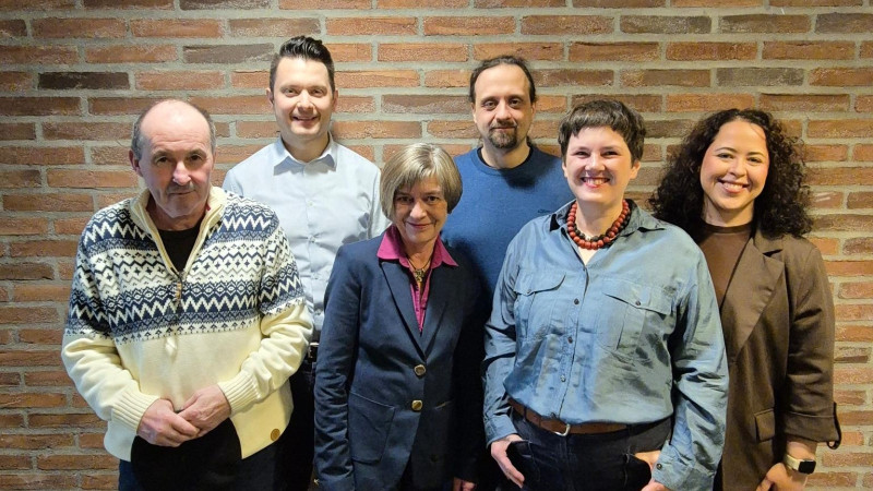 Sechs Personen vor einer Ziegelmauer